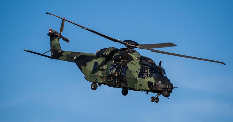 A green helicopter flying in the blue sky