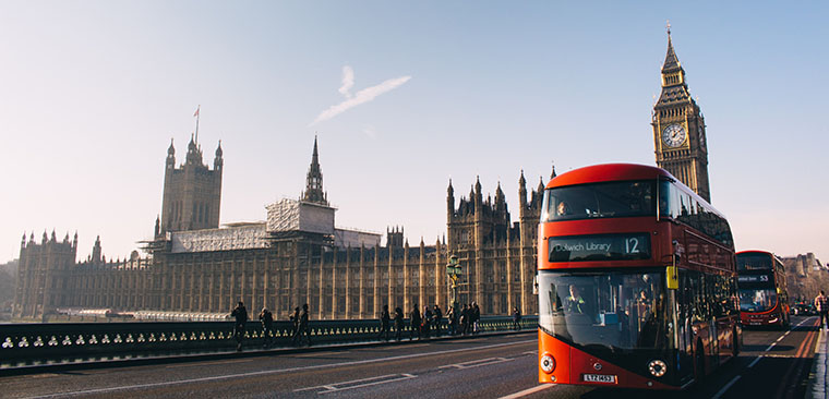 A view of Big Ben from a far and the red double-decker bus on the street