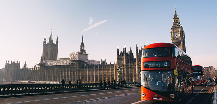 A view of Big Ben from a far and the red double-decker bus on the street