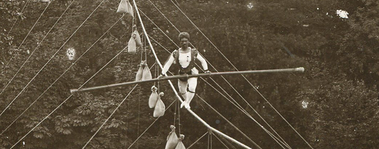 A black-and-white image of a tightrope walker performance
