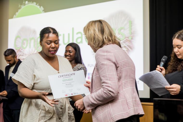 A woman handing a certificate to another woman at a conference