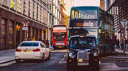 Traffic in a city with cars, buses, people, buildings on both sides of the road, etc.