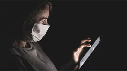 A person wearing medical mask and looking at a tablet's screen