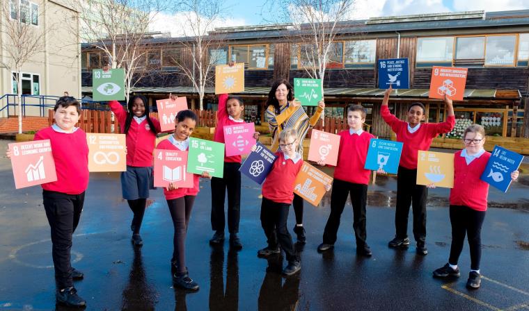 Primary school children and a teacher holding 17 UN Sustainable Development Goals boards