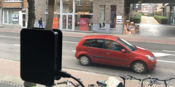 An empty street with a red car crossing by.