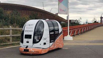 A white driverless pod on the path at the Olympic Park. 