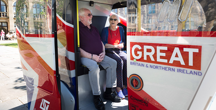 Two people sat in the back seat of a bus.