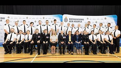 A group of police officers, seated in two rows, smiling at the camera