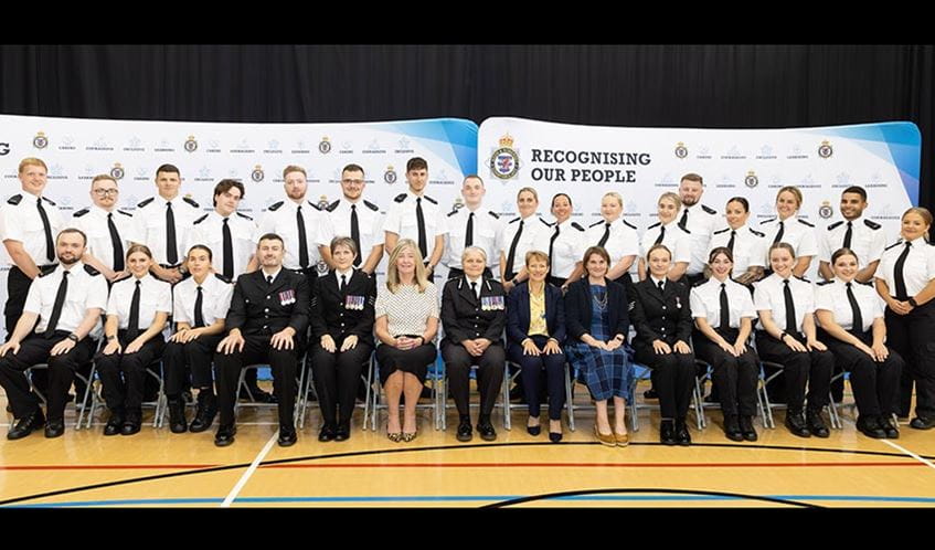 A group of police officers, seated in two rows, smiling at the camera