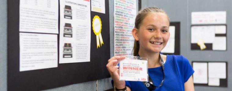 Young girl holding Engineering Leadership winner badge.