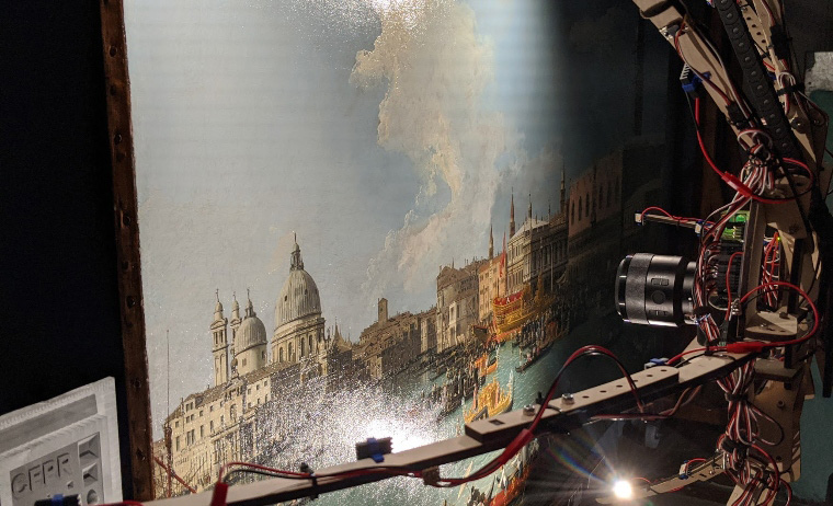 A scanner scans a piece of artwork showing a scene in Venice with boats in front of some older buildings.