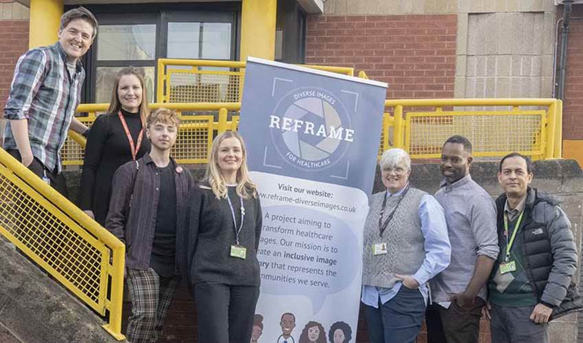 Image of a group of seven people smiling at the camera while stood outside a community hall in Bristol