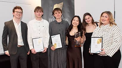 Six men and women looking at the camera and smiling, with several holding prizes in their hands. 