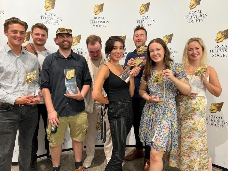 Group of eight award winners posing with their awards.