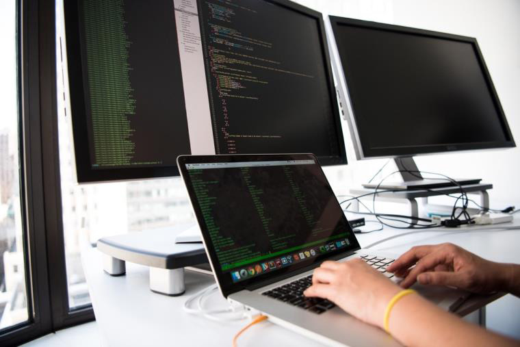 Someone using four computer monitors to code.