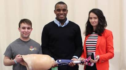 Dr Etoundi, Mike Rose and Mayur Hulke together holding a prosthetic leg.