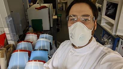 A technician taking a selfie in front of PPE giving a thumbs up.