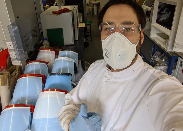 A technician taking a selfie in front of PPE giving a thumbs up.