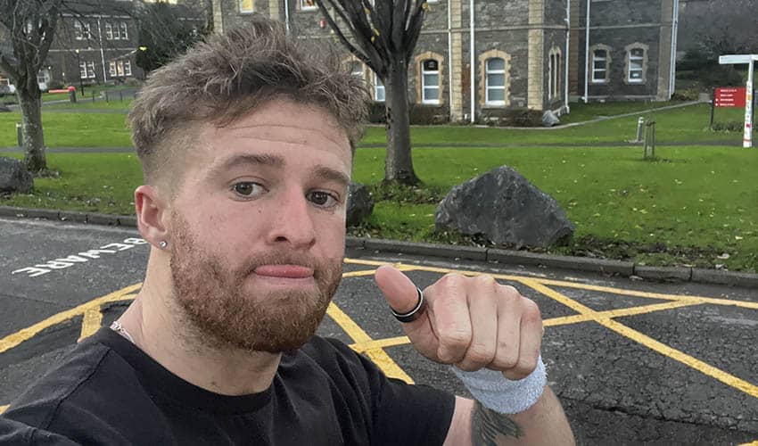 A man wearing a black T-hirt giving a thumbs up to the camera