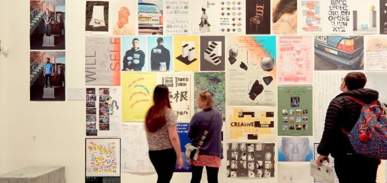 People looking at wall of artwork.