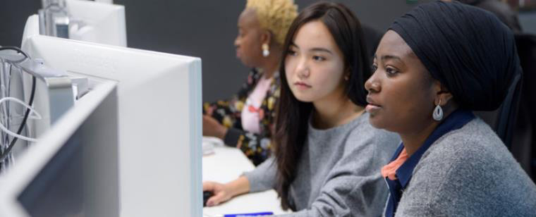Two women viewing a computer monitor.