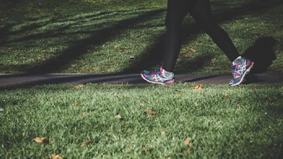 Close up of someone's legs, wearing sports leggings and trainers, walking in a park.