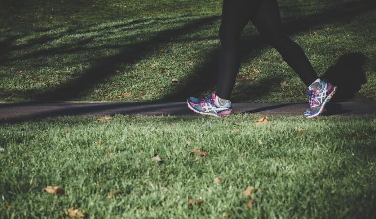 Close up of someone's legs, wearing sports leggings and trainers, walking in a park.