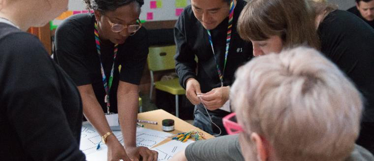 People working on an artistic project on a table.