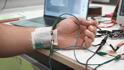 Wearable health monitoring e-textiles being tested on someone's wrist in a laboratory environment. 