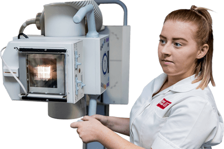 Technician in white overcoat moving large white machine.