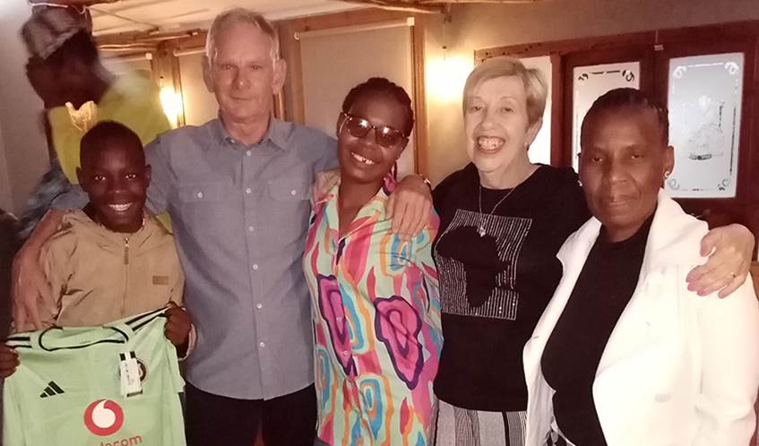 A group of people including a young boy on the left smile happily at the camera