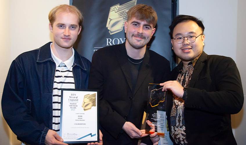 A group of three students smile at the camera, while holding an award and certificate.