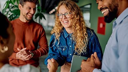 People standing together in conversation, with one person shaking hands in an office setting.
