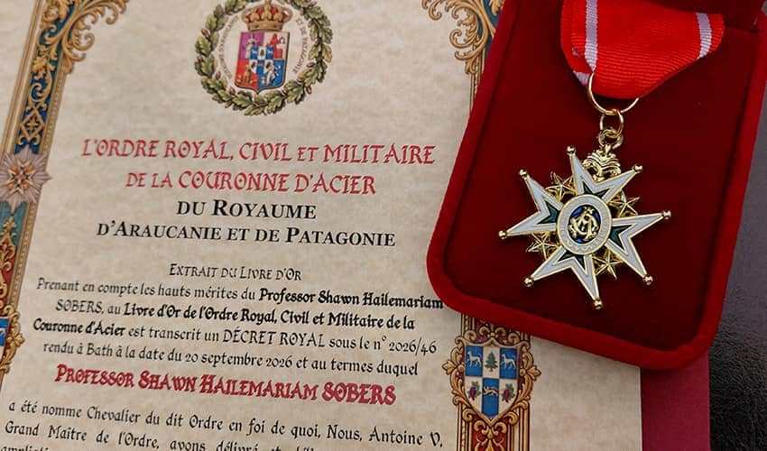 A certificate naming Professor Shawn Halemariam Sobers a Knight of the Royal, Civil and Military Order of the Crown of Steel of the Kingdom of Araucania and Patagonia, displayed beside an ornate star-shaped medal in a red presentation case.
