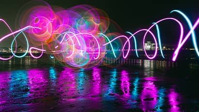 A colourful display of twirling lights above water.
