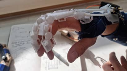 A close up picture shows an exoskeletal bionic glove covering a hand. 