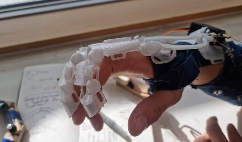 A close up picture shows an exoskeletal bionic glove covering a hand.