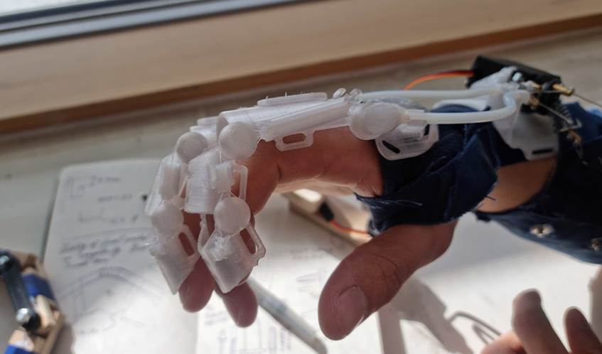 A close up picture shows an exoskeletal bionic glove covering a hand.