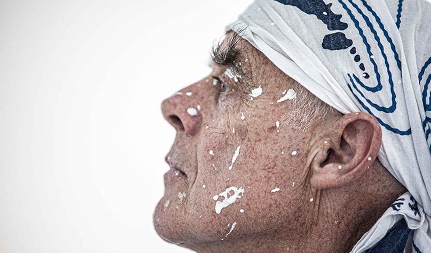 The side profile of a man wearing a white bandana with white paint on his face