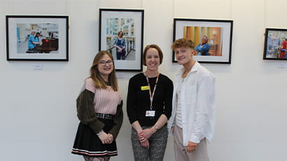 Students Carla Mabb and  Kian Swainston, with arts programme manager Donna Baber stand in front of the photography exhibition at the Brunel building
