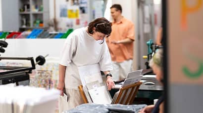 A woman looks at prints in an art studio.  