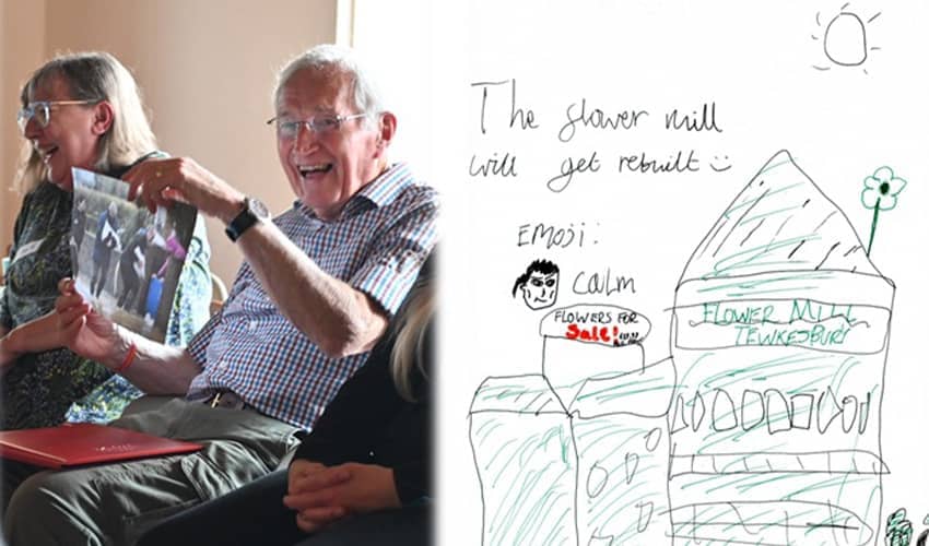 An older man sits beside a smiling woman; next to them, artwork by a child reads “Tewkesbury in 2030” with simple drawings about rebuilding the Flower Mill.