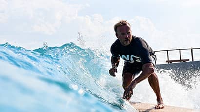 A man in a black rash vest riding a surfboard 