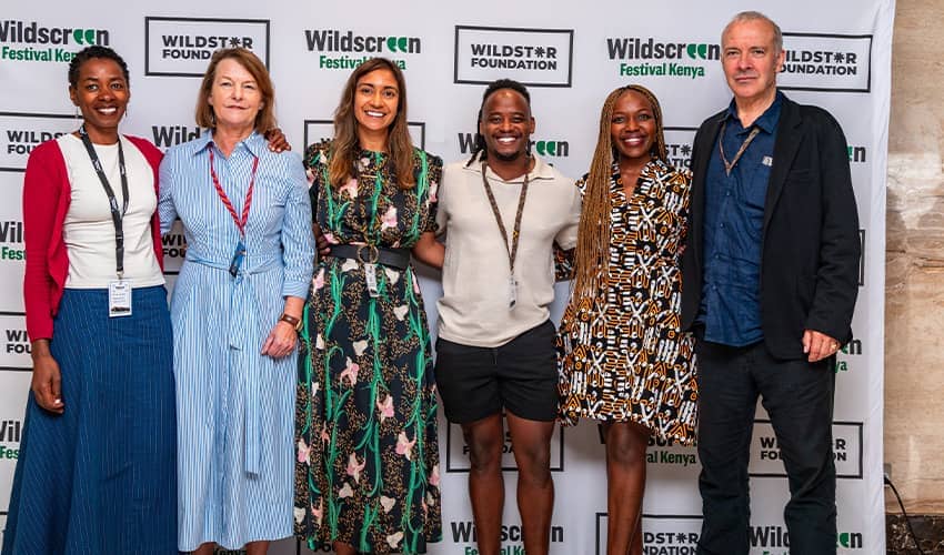 A group of six people stand in a line, smiling at the camera with Wildscreen branding behind them.