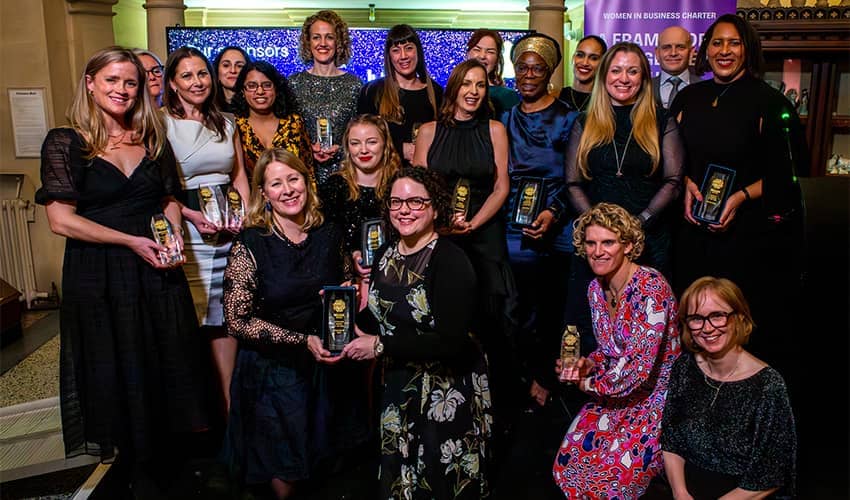 A large group of women gathered holding awards smiling at the camera.