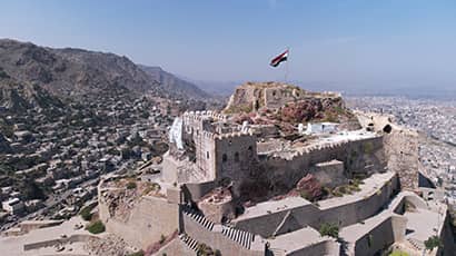 An historic castle sits high up on a hillside overlooking a city.
