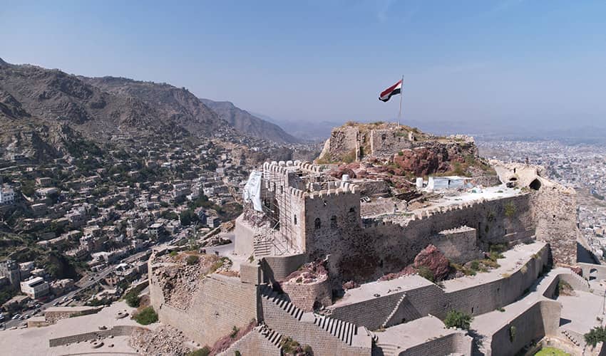 An historic castle sits high up on a hillside overlooking a city.