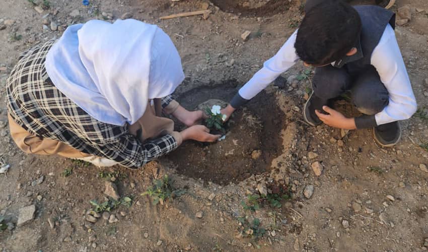 Two children planting a plant. 