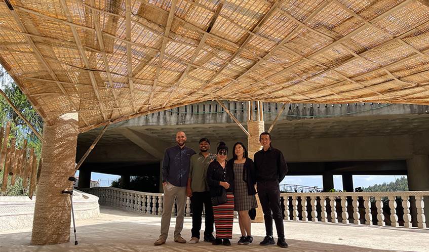 L-R UWE Bristol students Jos Searle, Austin Danabal, global partnerships lead Mian Ng, and students Mandy Lim and Wei Hong Teh Five people stood underneath a large bamboo structure