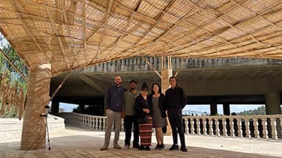 Five people stood underneath a large bamboo structure 